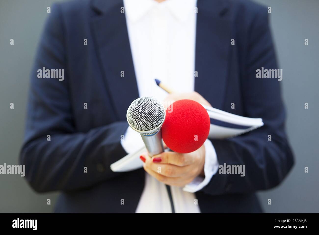 Journalistin bei Pressekonferenz, Schreiben von Notizen, mit Mikrofon Stockfoto