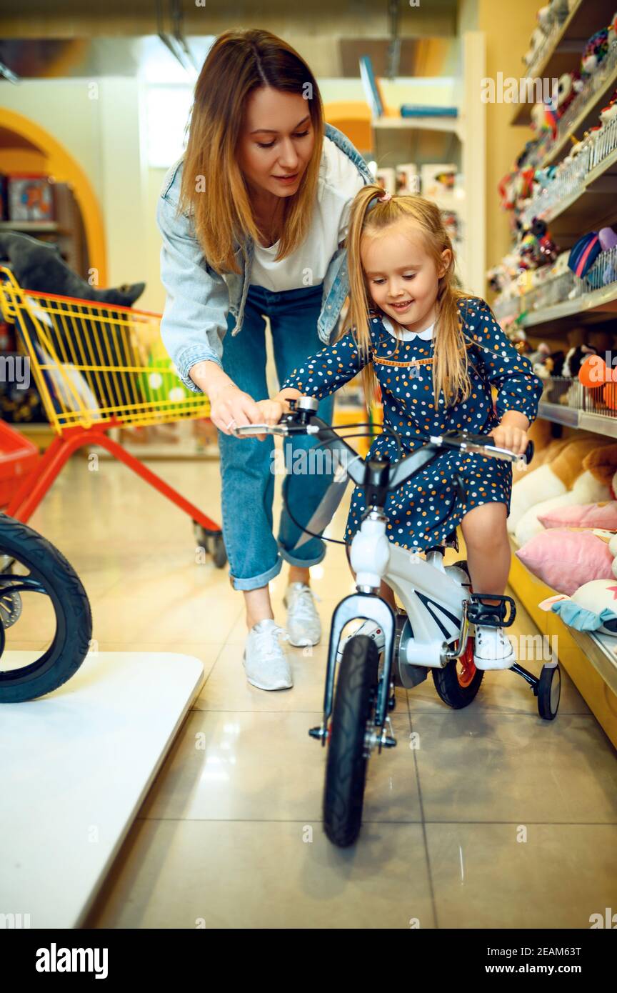 Mutter und kleines Mädchen Wahl Fahrrad, Kindergeschäft Stockfoto