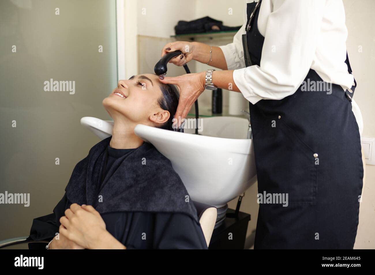 Friseur wäscht Frauenhaare, Friseursalon Stockfoto