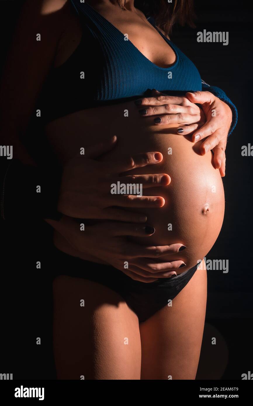 Schwangere Frau mit den Händen ihres Mannes auf ihr Bauch Stockfoto