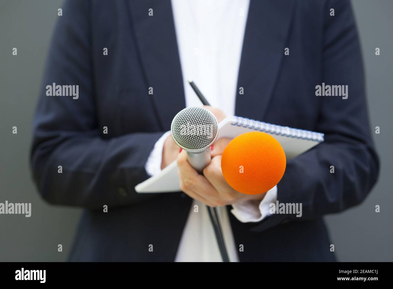 Nachrichtenreporter oder Journalist bei der Pressekonferenz, hält Mikrofon und schreibt Notizen Stockfoto