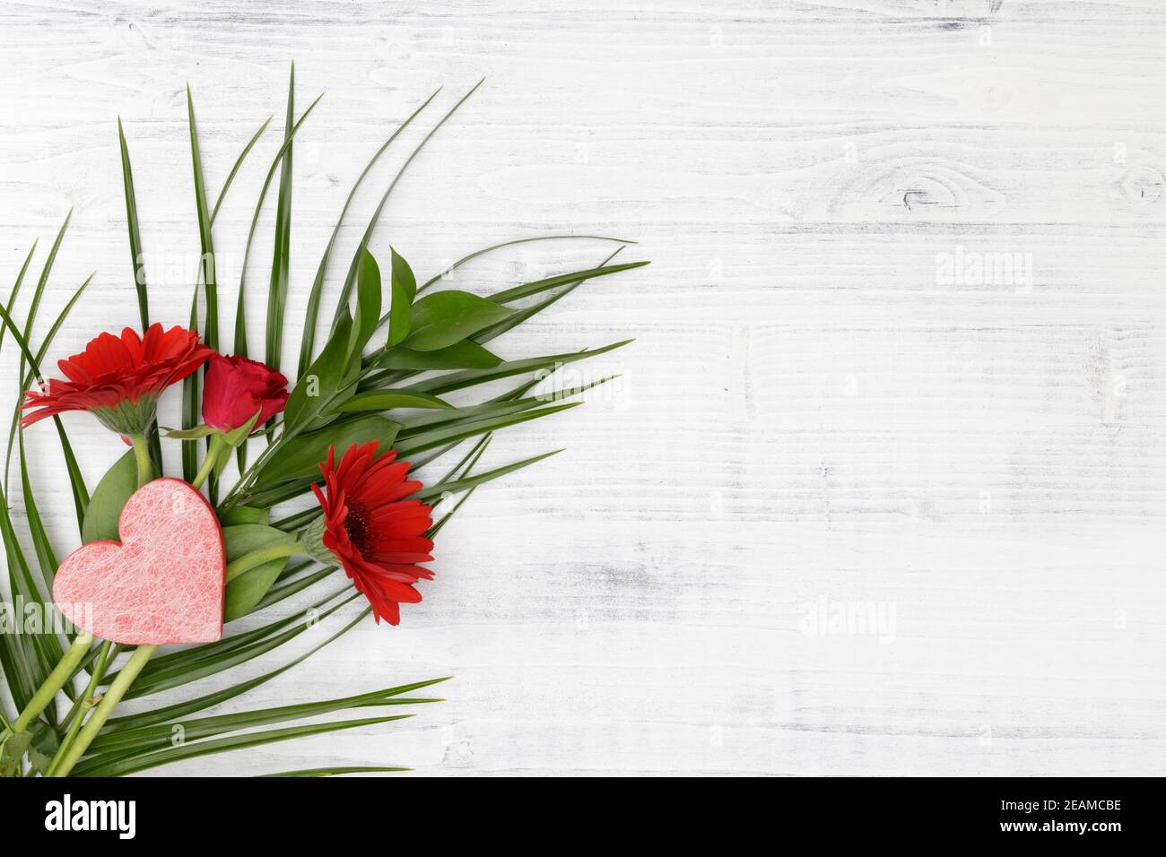 Rote Blumen mit rotem Herz auf weißem Holzhintergrund Stockfoto