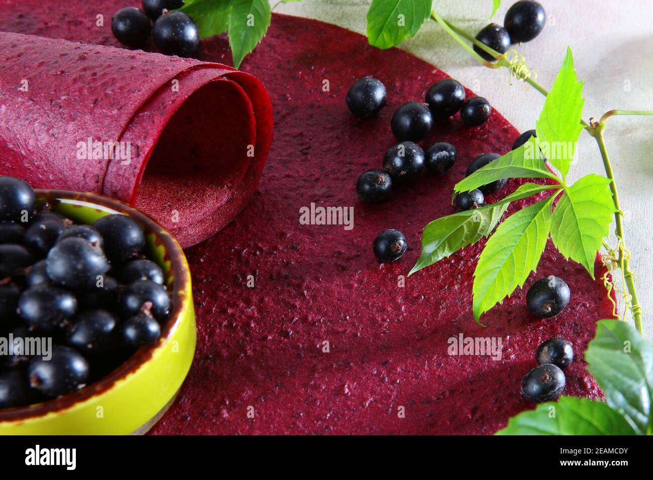 Schwarze Johannisbeere Pastilla. Natürliches und gesundes Produkt. Vegetarisches Essen. Hopfenzweig mit grünen Blättern. Johannisbeeren in keramischen Gerichten. Draufsicht. Stockfoto