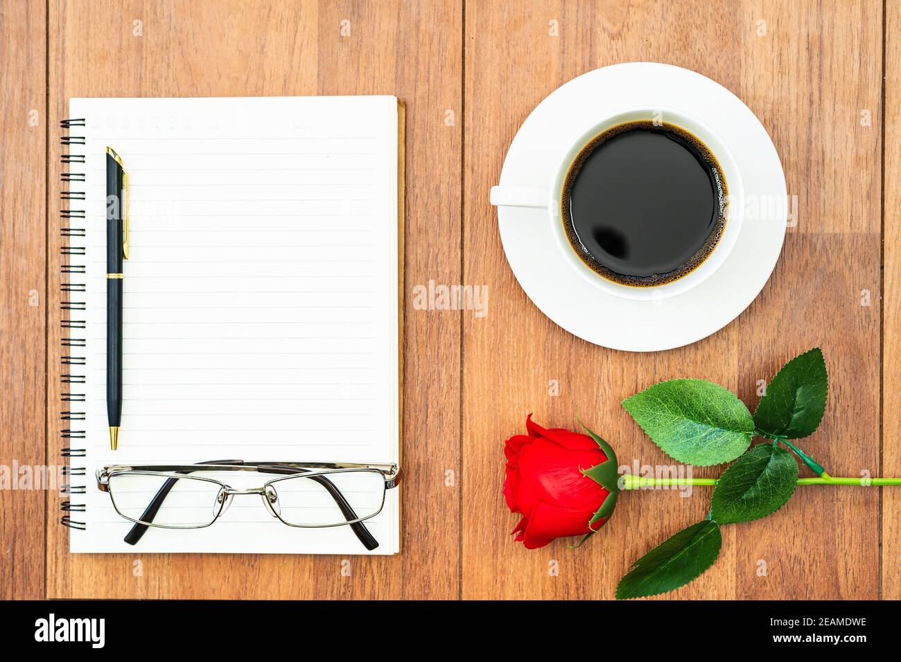 Valentinstagskonzept, rote Rosen auf Holztisch und Notizblock Stockfoto