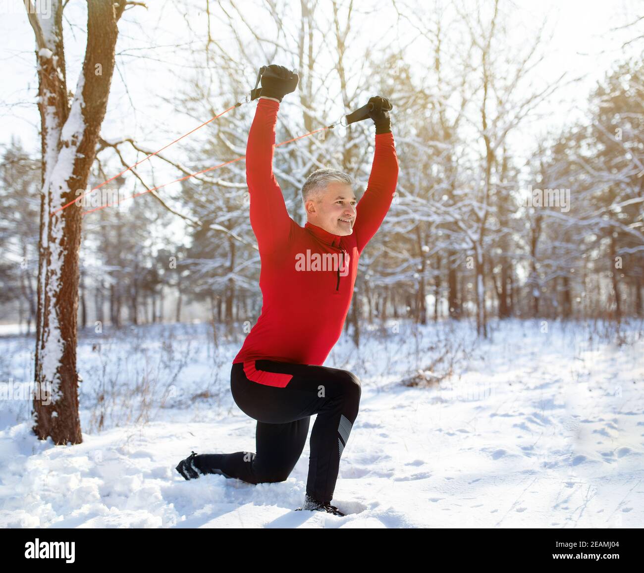 Funktionelles Fitness-Workout im Freien. Reifer Mann mit Bodyweight Widerstand Riemen, dabei Ausfallschritte im verschneiten Winter Park Stockfoto