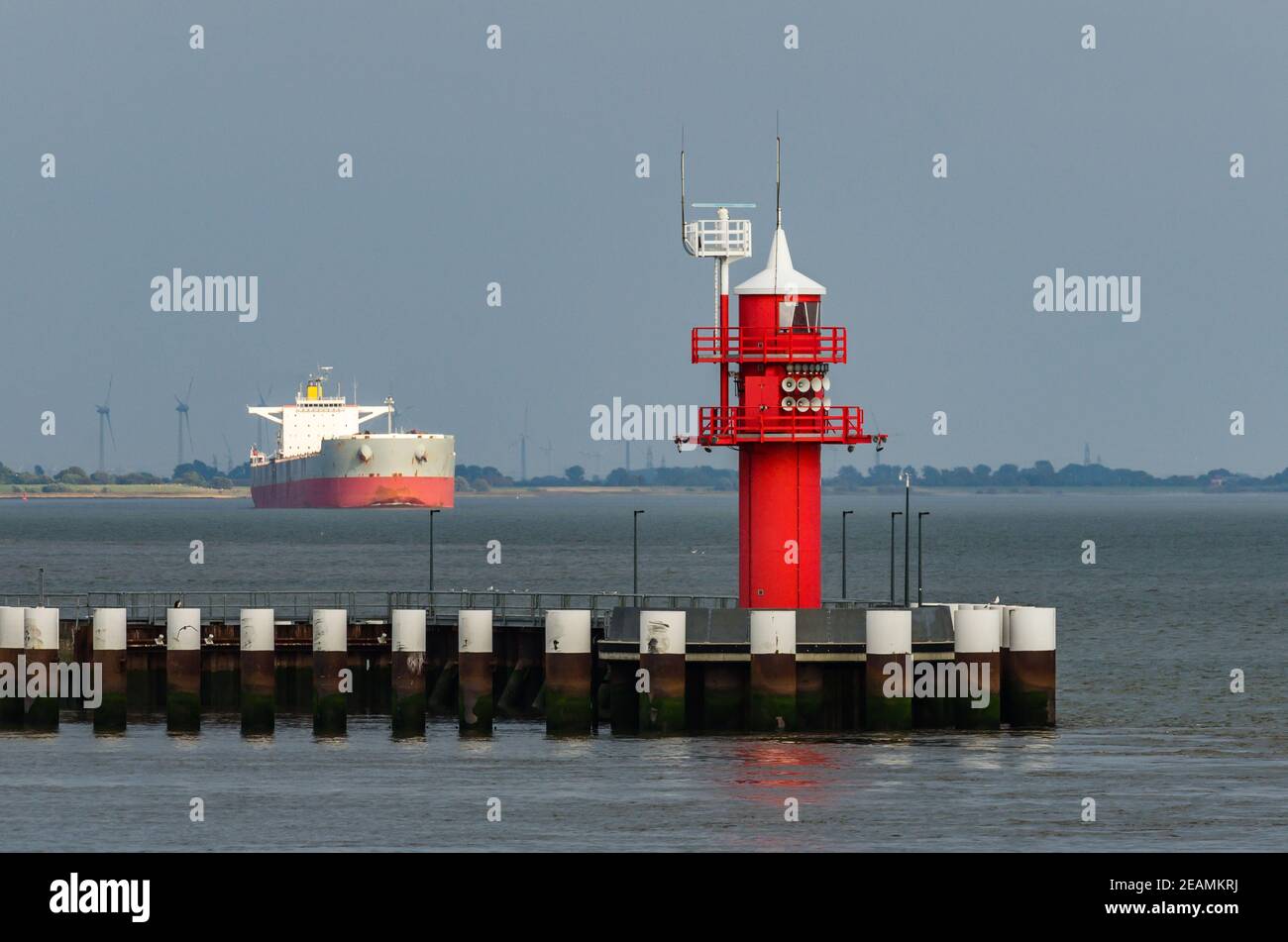 Leuchtturm mit Frachtschiff im Hintergrund, Brunsbüttel, Schleswig-Holstein, Nordsee, Deutschland Stockfoto