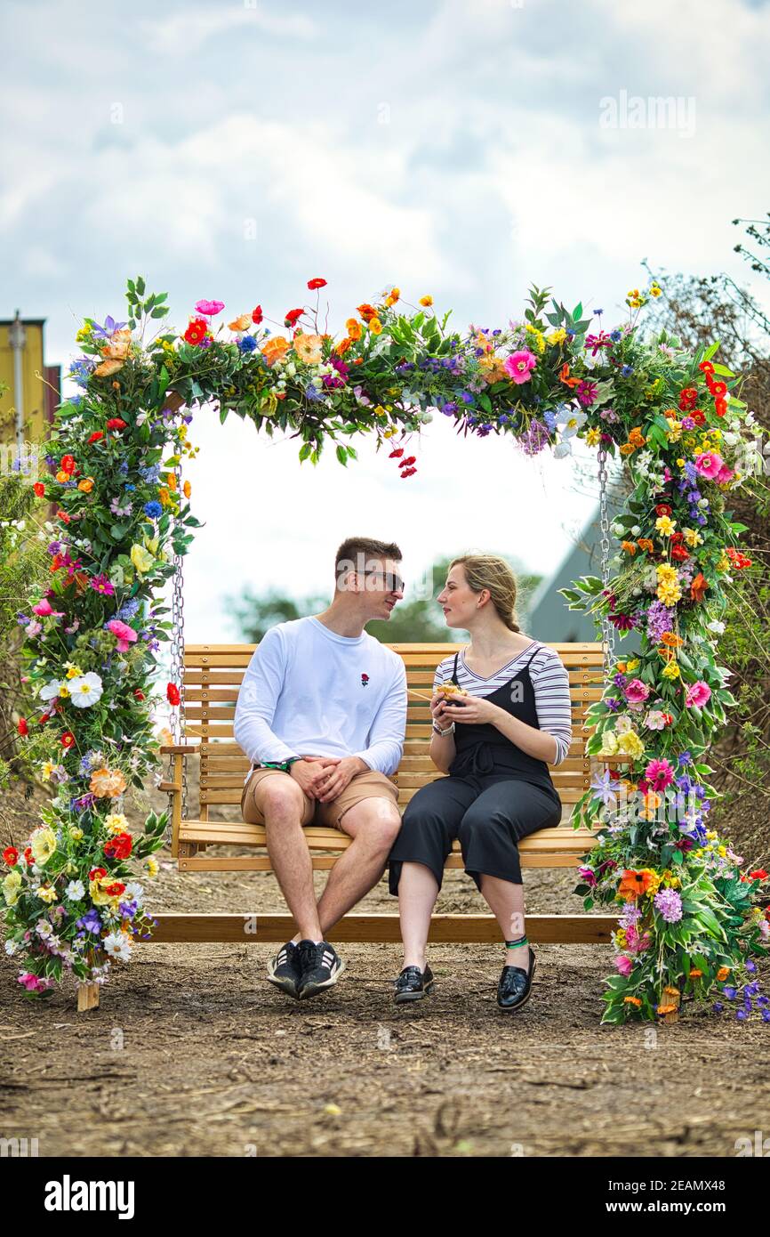 Junges Paar auf Holzschaukel im Freien sitzen Stockfoto