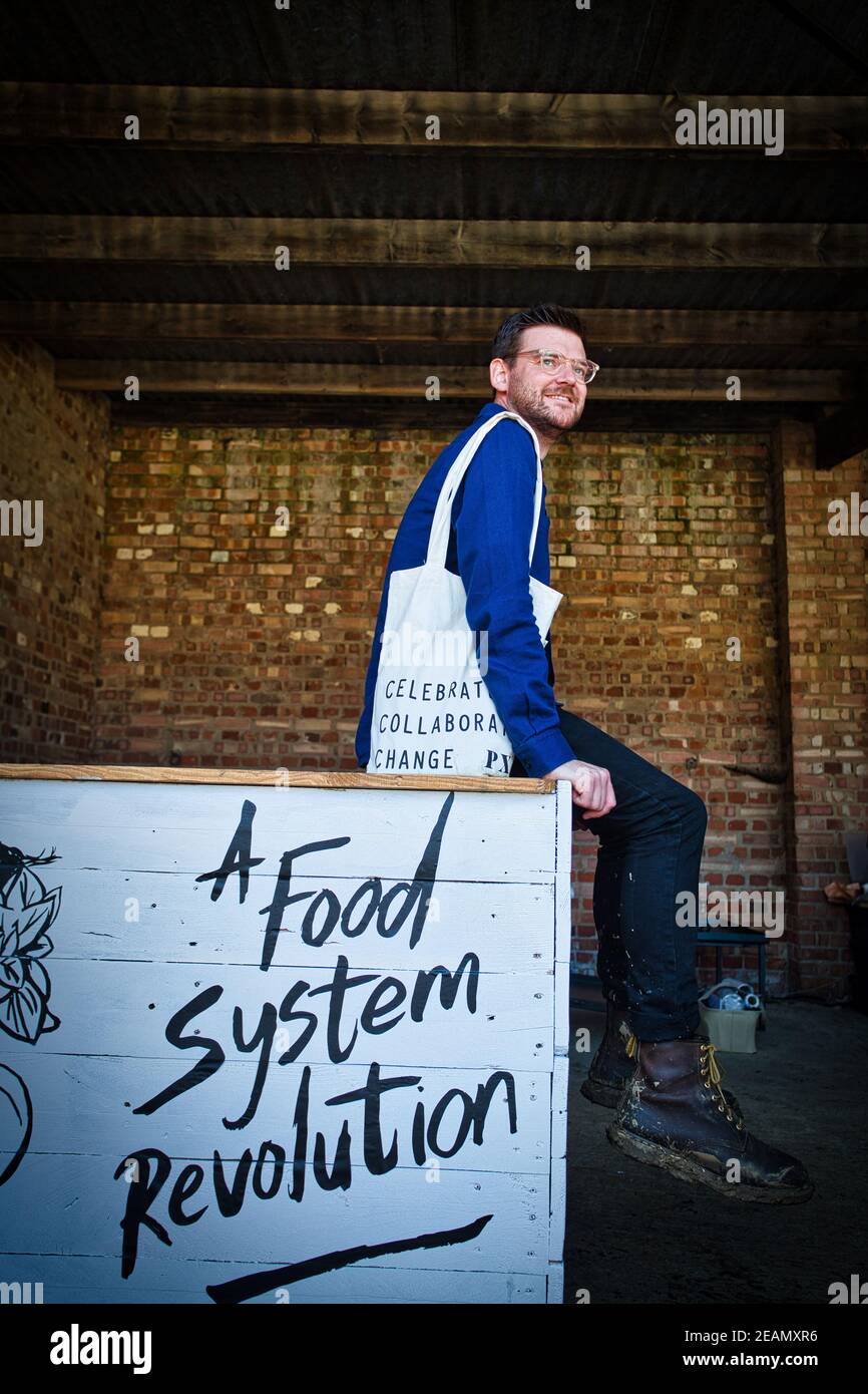 Mann sitzt am Tisch mit dem Slogan eine Revolution des Ernährungssystems . Stockfoto