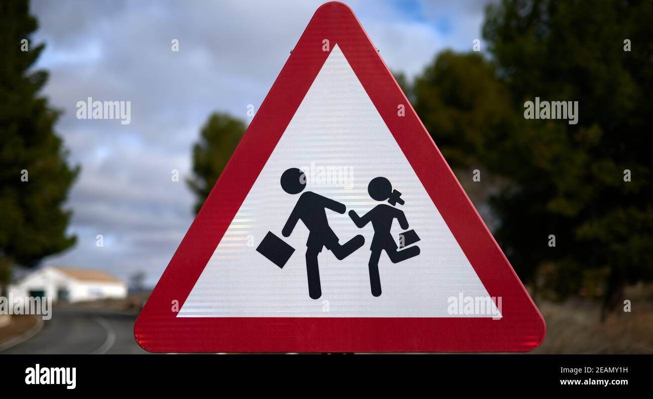 Detail eines dreieckigen Verkehrsschildes mit roter Grenze und weißem Hintergrund, der den Durchgang der Kinder zur Schule darstellt. Stockfoto