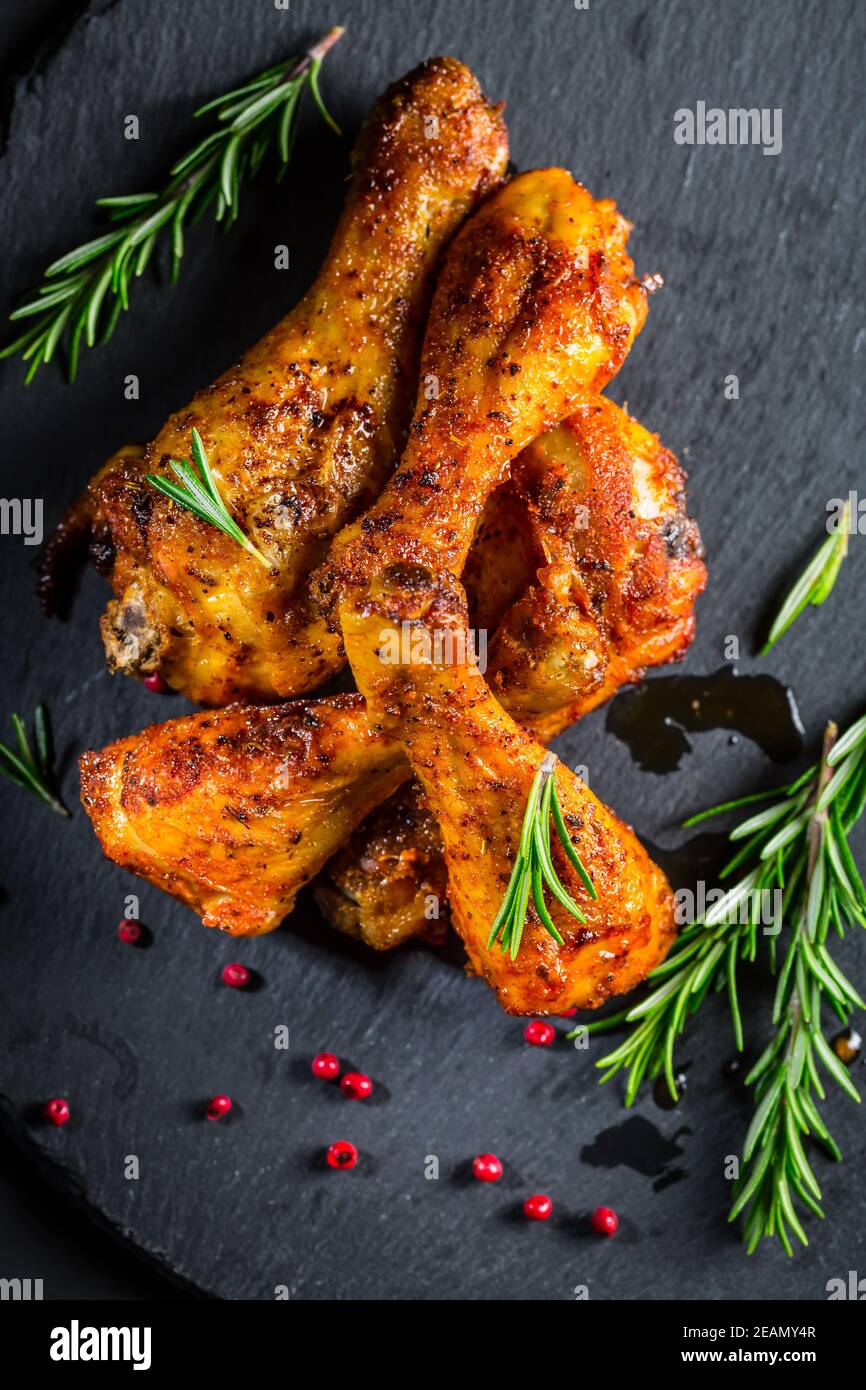Scharf würzige Hähnchenbeine mit Kräutern auf schwarzem Hintergrund Stockfoto