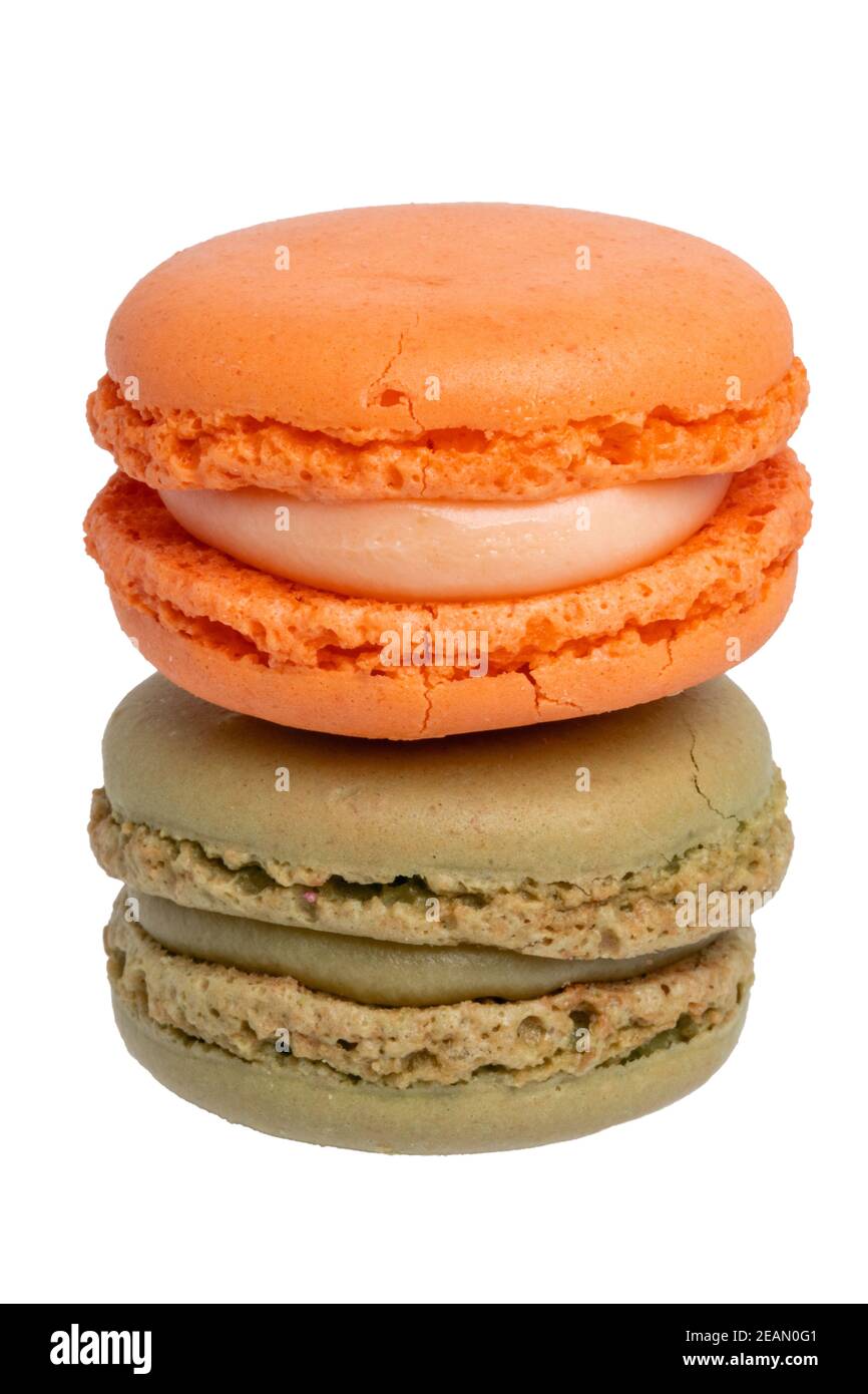 Gebäck, Desserts und Süßigkeiten. Nahaufnahme eines orangen Makronen und eines grünen Pistazien-Makronen isoliert auf weißem Hintergrund. Makrofotografie. Stockfoto