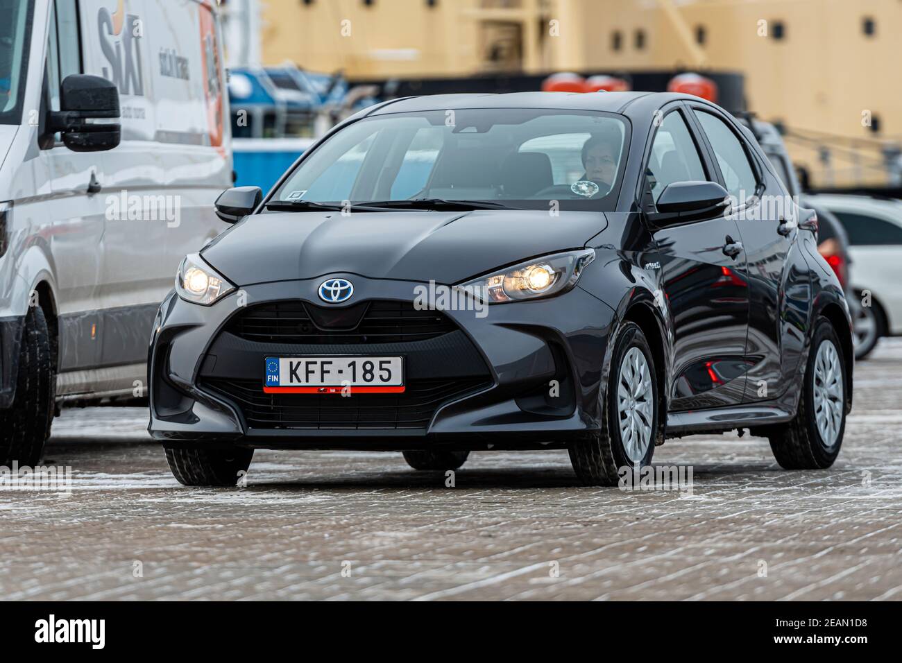 Riga, Lettland - 9. Februar 2021: Graumetallisches Toyota Yaris Hybrid Y20 Edition Auto auf einem industriellen Hintergrund Stockfoto