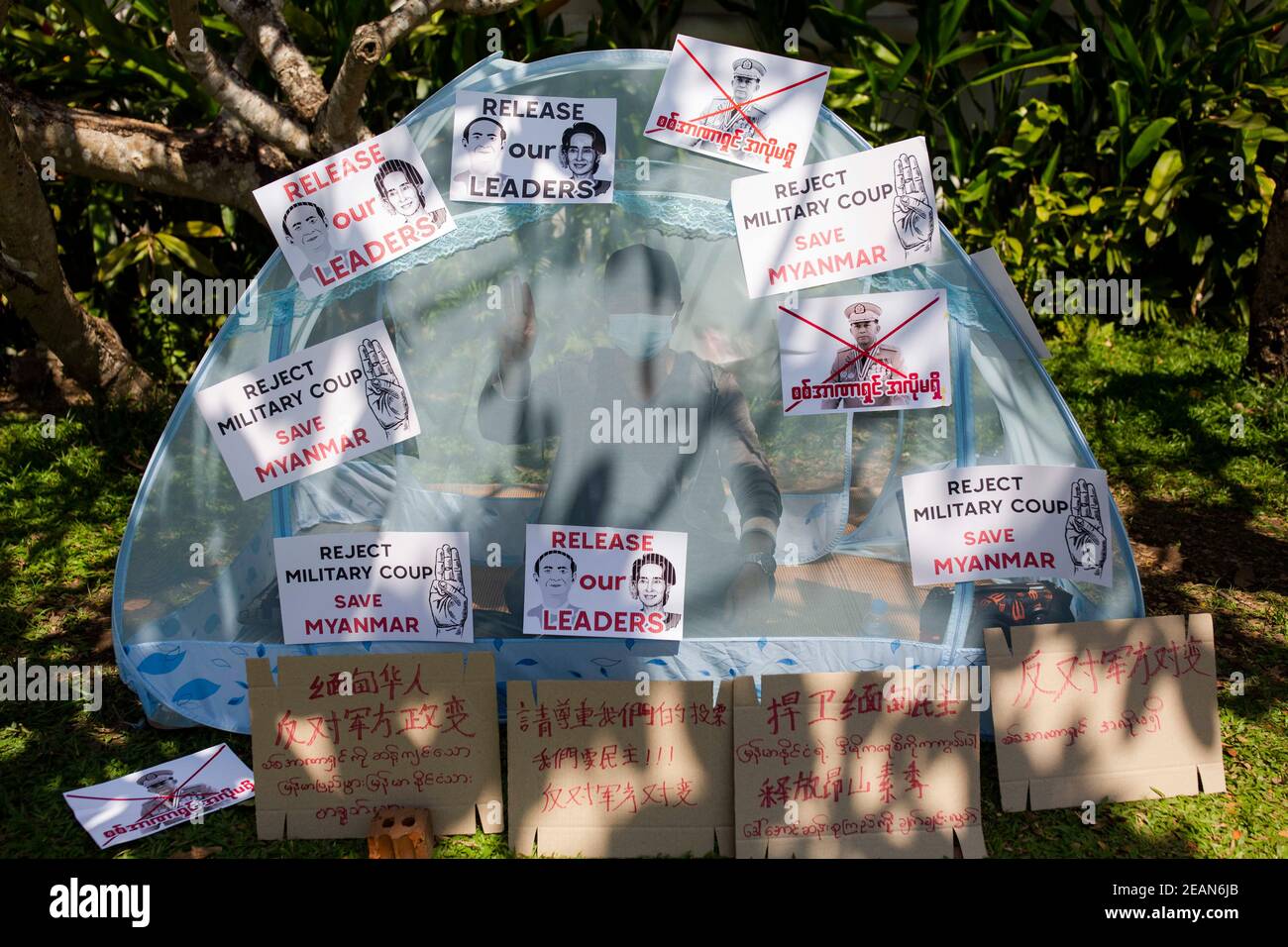 Während des Militärputsches sitzt ein Protestler in einem Zelt, das mit Protestlosungen bedeckt ist.Tausende Menschen gingen am fünften Protesttag gegen den Militärputsch auf die Straßen von Yangon und forderten die Freilassung von Aung San Suu Kyi. Das Militär von Myanmar nahm am 01. Februar 2021 die staatliche Beraterin von Myanmar Aung San Suu Kyi fest und erklärte den Ausnahmezustand, während sie die Macht im Land für ein Jahr ergattete, nachdem sie die Wahl gegen die National League for Democracy (NLD) verloren hatte. Stockfoto