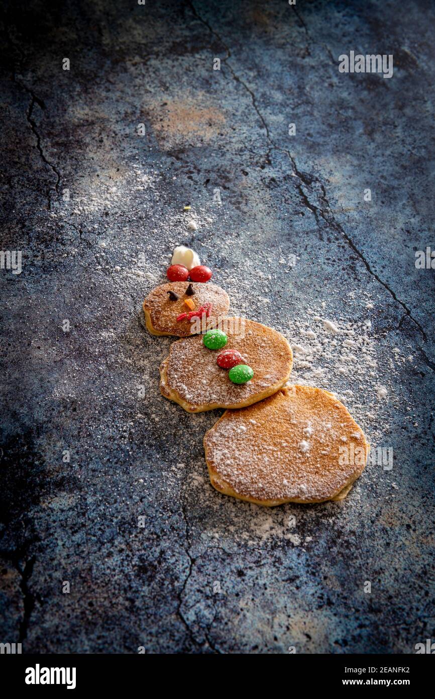 Niedliche verzierte Pfannkuchen in Form von Schneemann auf Tischhintergrund von Kindern für Weihnachten, Italien, Europa gemacht Stockfoto