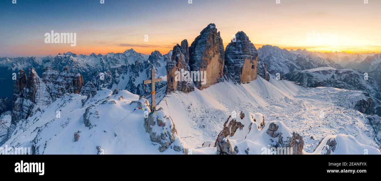 Gipfelkreuz auf schneebedeckter Monte Paterno mit Tre Cime Di Lavaredo im Hintergrund bei Sonnenuntergang, Sextner Dolomiten, Südtirol, Italien, Europa Stockfoto