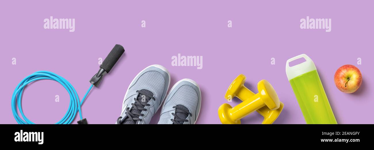 Fitnessgeräte auf fliederfarbenem Hintergrund mit Copyspace Stockfoto