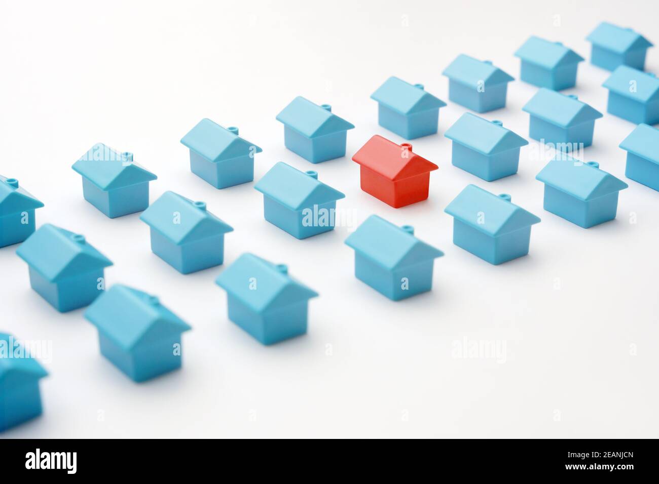 Miniatur rot Modell Haus unterscheidet sich von Gruppe blau Spielzeug gleichen Typ Häuser auf weiß. Auswahl Immobilien oder Immobilienmarkt in Cottage Village oder Stockfoto