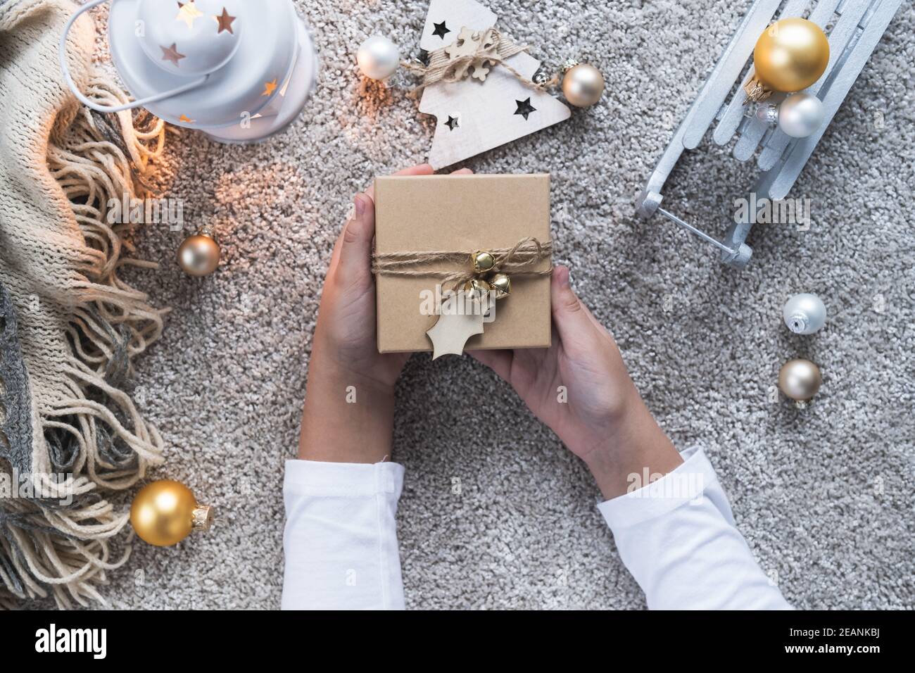 Weihnachtshintergrund mit gemütlicher Winteratmosphäre. Kinderhände mit dem Geschenk für das neue Jahr. Stockfoto