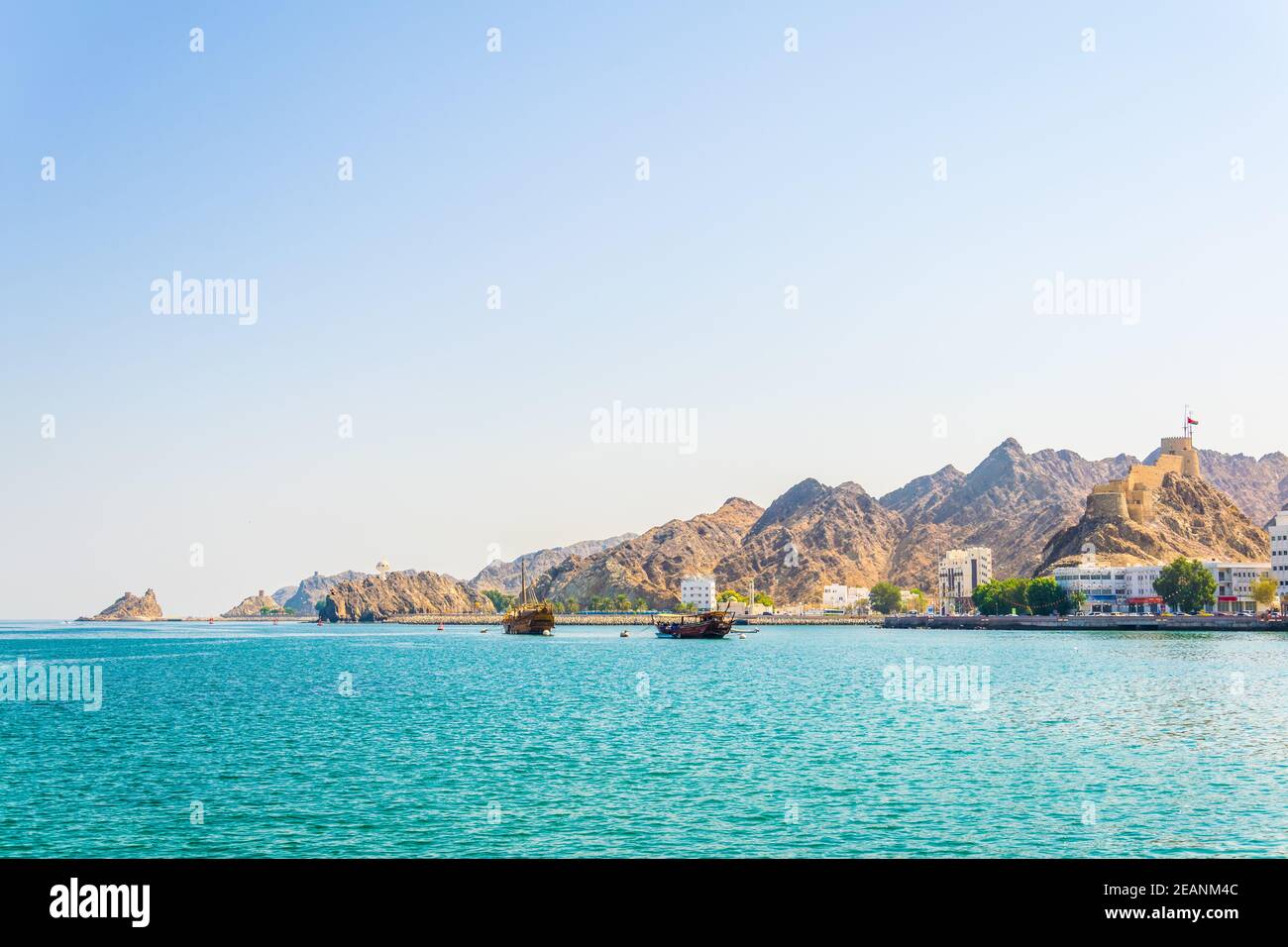 Ein Paar Daus - traditionelle arabische Schiffe - ist auf dem Weg zum Meer von Muttrah Teil von Muscat dominiert von einem Fort auf einem Hügel, Oman. Stockfoto