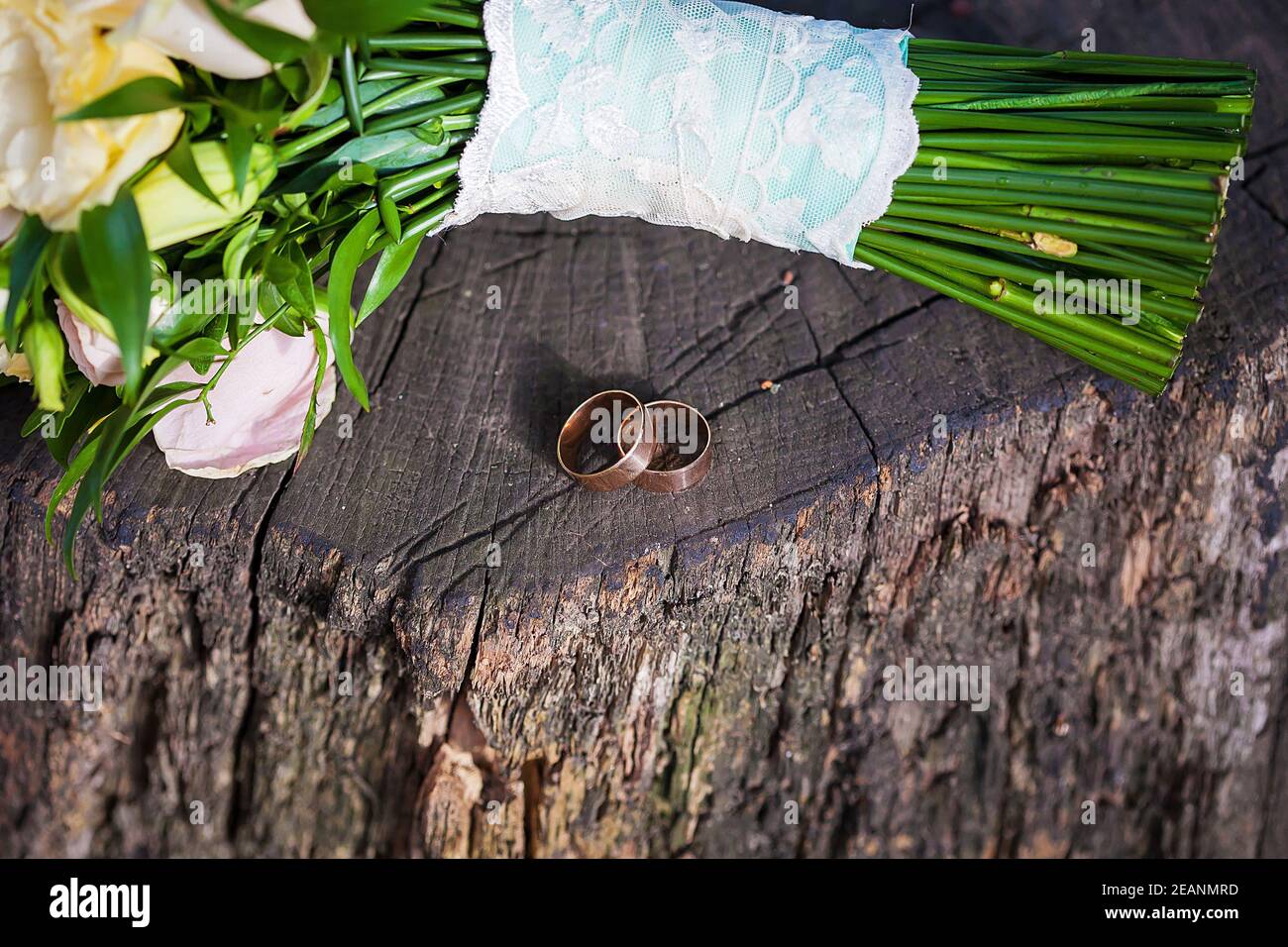 Schöne zwei Eheringe auf Holzstumpf und ein Stück Des Bouquets Stockfoto