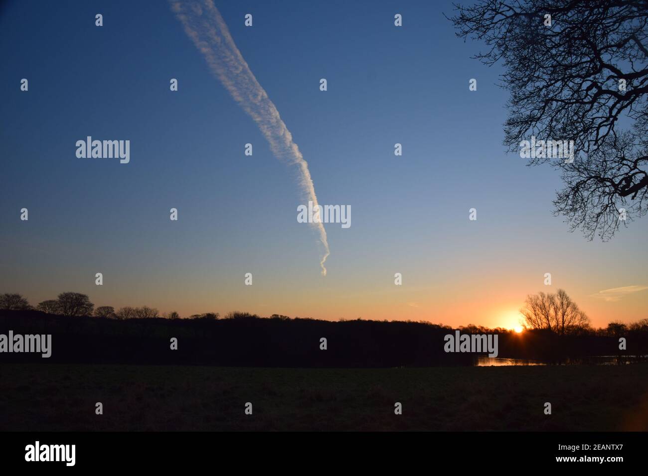 Die aufgehende Sonne und ein Jetstream treffen sich am Horizont. Stockfoto
