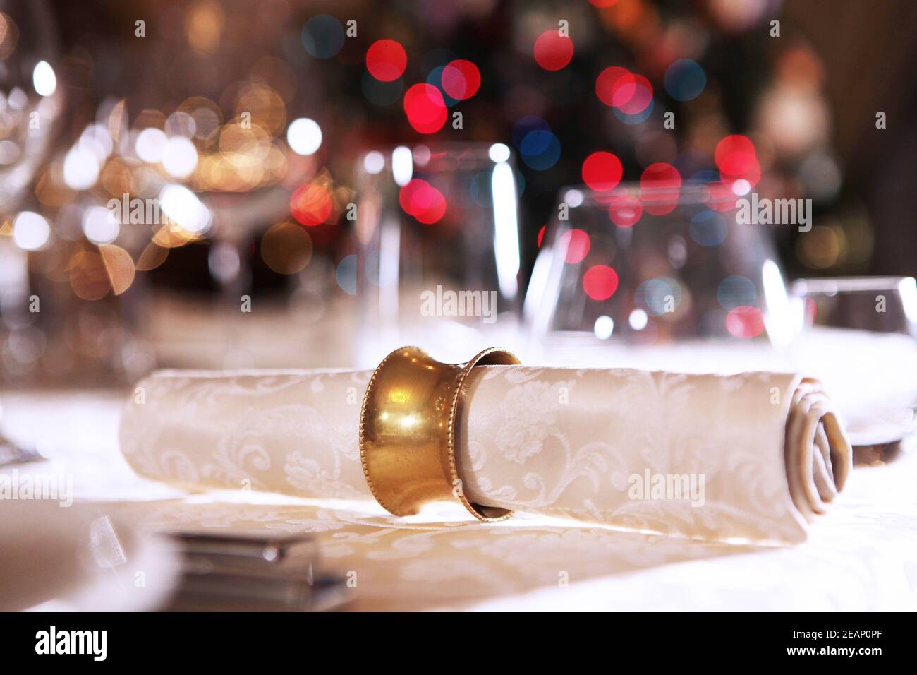 Wunderschöne weihnachtliche Tischeinstellung. Die Serviette ist auf dem Teller. Makrofoto auf dem Hintergrund eines Weihnachtsbaums. Stockfoto