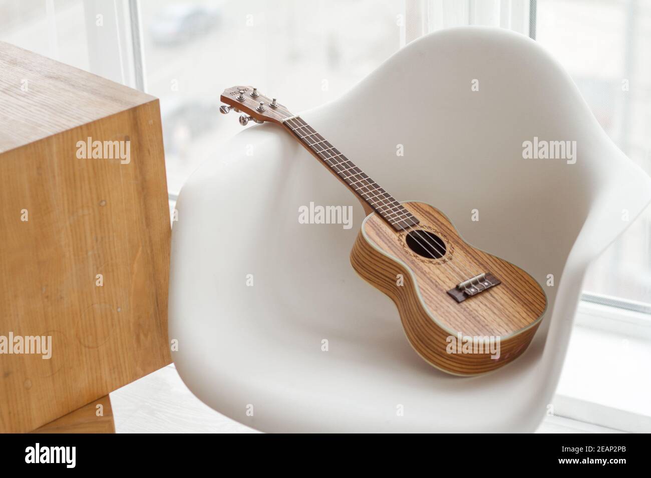 Gitarre Ukulele auf weißem Hocker, Gitarre spielen lernen, Raum kopieren  Stockfotografie - Alamy