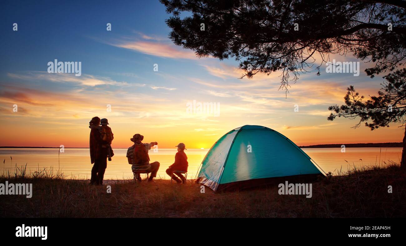 Familie ruht mit Zelt in der Natur bei Sonnenuntergang Stockfoto