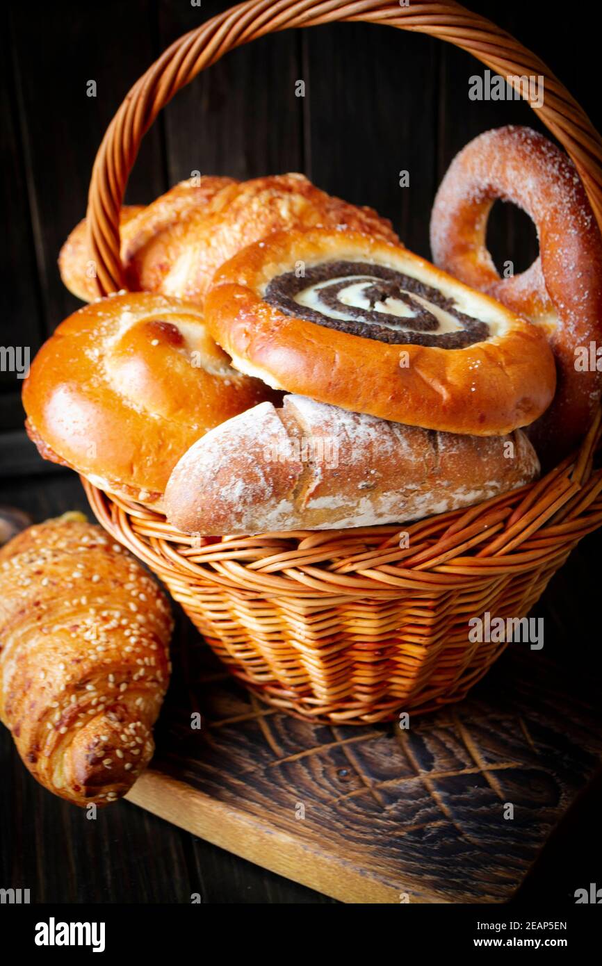 Zusammensetzung mit Brot und Brötchen in Korbkorb auf dunkel Hintergrund Stockfoto