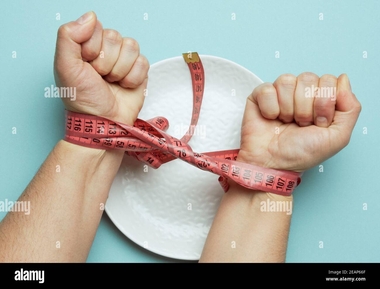 Zwei weibliche Hände gebunden mit rotem Maßband auf einem Weiße runde Keramikplatte Stockfoto