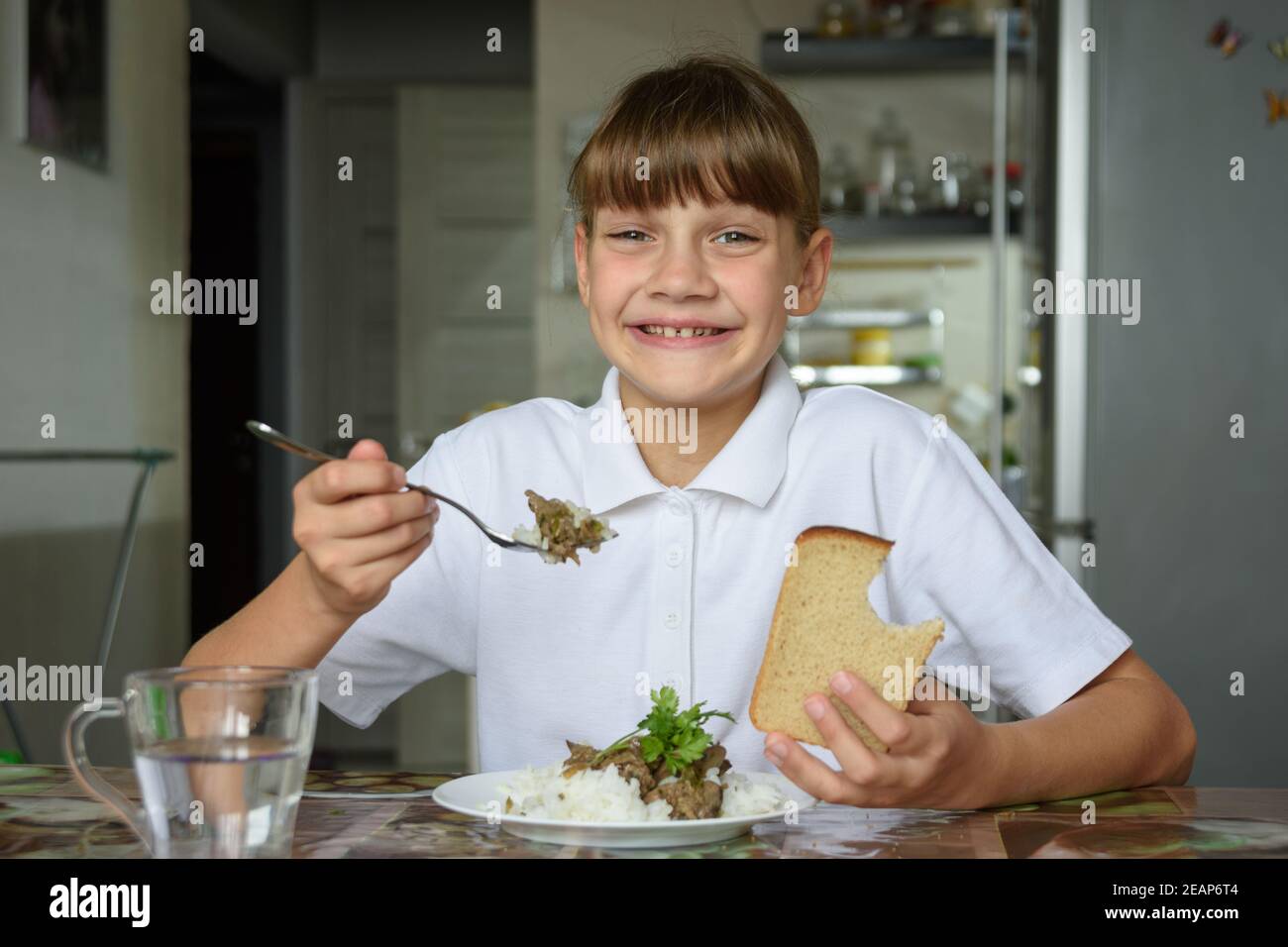 Glückliches Mädchen isst glücklich das zweite Gericht und schaut hinein Der Rahmen mit einem niedlichen Lächeln Stockfoto