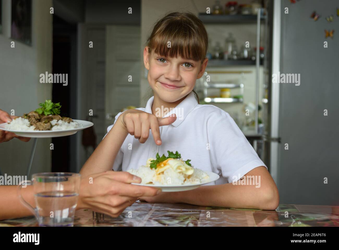 Glückliches Mädchen wählte ein Gericht aus zwei angeboten von Ihre Mutter zum Mittagessen Stockfoto