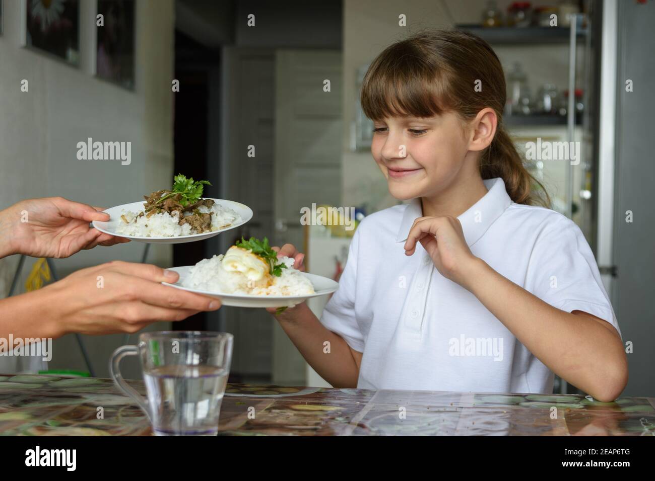 Mama bietet dem Mädchen zwei verschiedene Gerichte zum Mittagessen Stockfoto