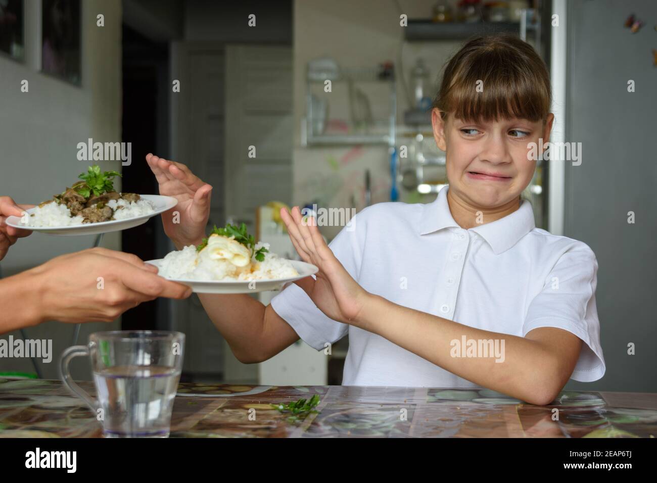 Das Mädchen am Esstisch lehnt das angebotene Essen ab Stockfoto