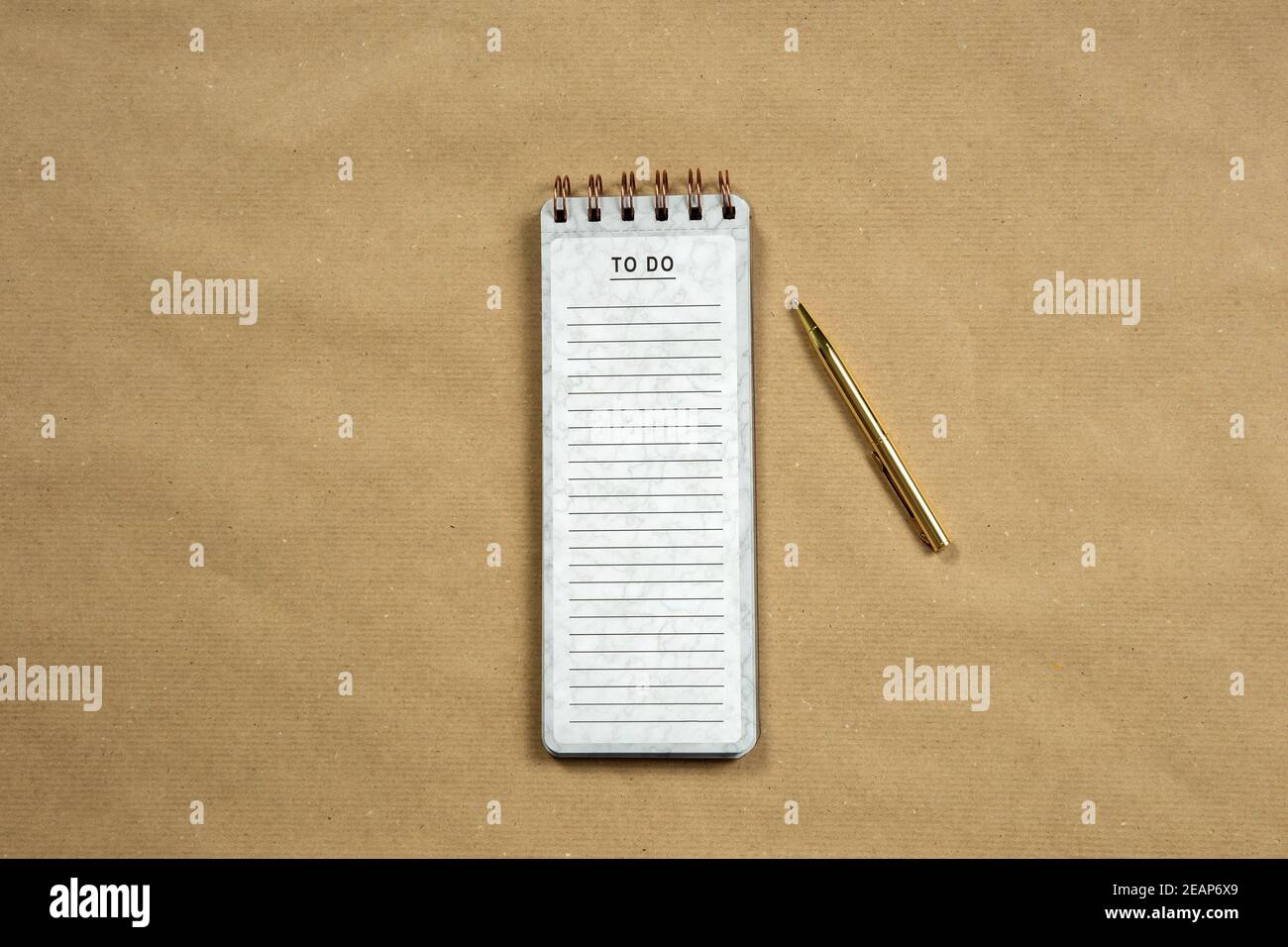 Draufsicht auf leeren Notizblock mit leerer To Do-Liste auf braunem Papierhintergrund, Kopierraum oder Platz für Text, modernes Design mit Goldstift Stockfoto