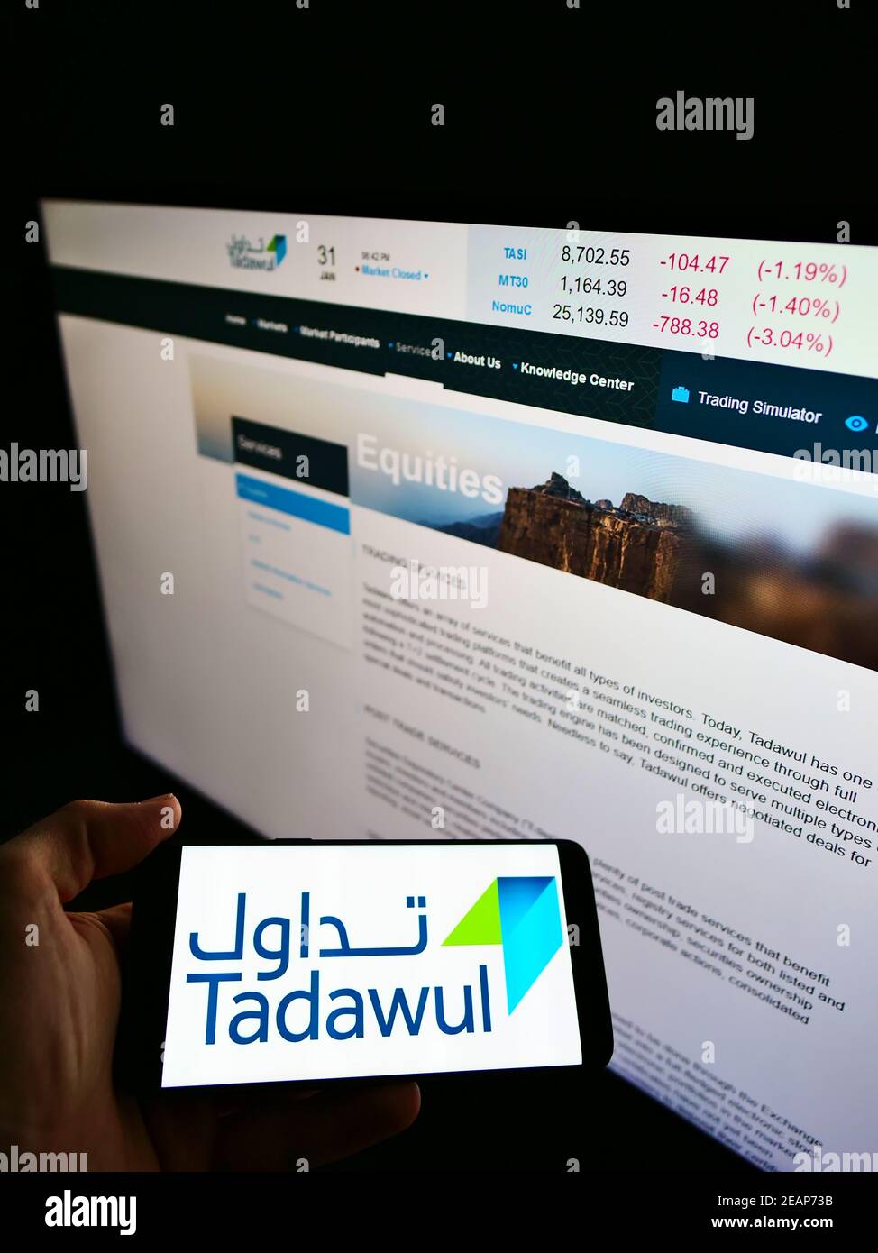 Person hält Handy mit Firmenlogo der Saudi-arabischen Börse Tadawul auf dem Bildschirm mit Website im Hintergrund. Konzentrieren Sie sich auf die Telefonanzeige. Stockfoto