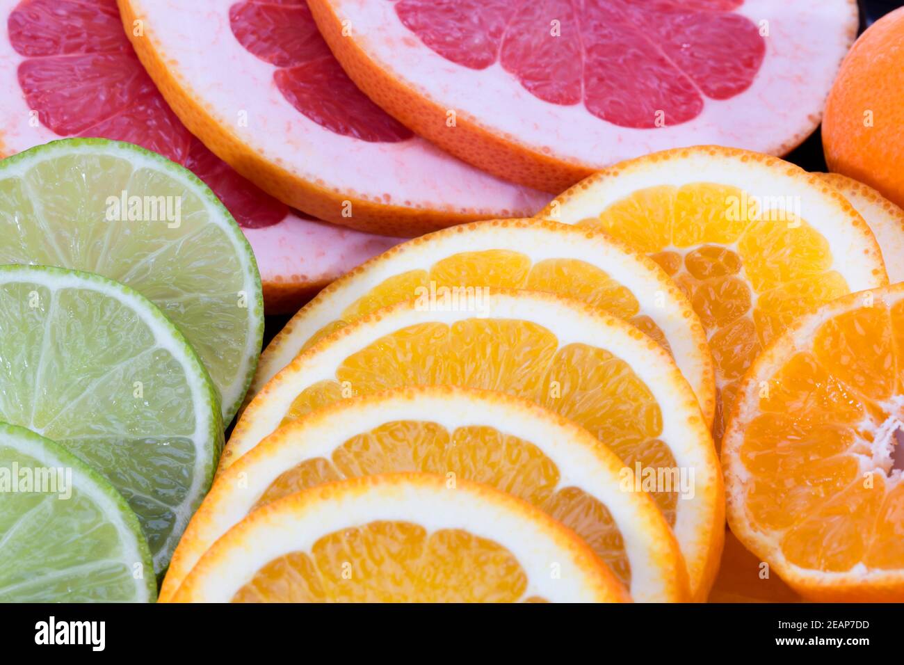 Hintergrund von Fruchtscheiben aus roter Grapefruit, grüner Limette und Mandarine, Nahaufnahme Stockfoto