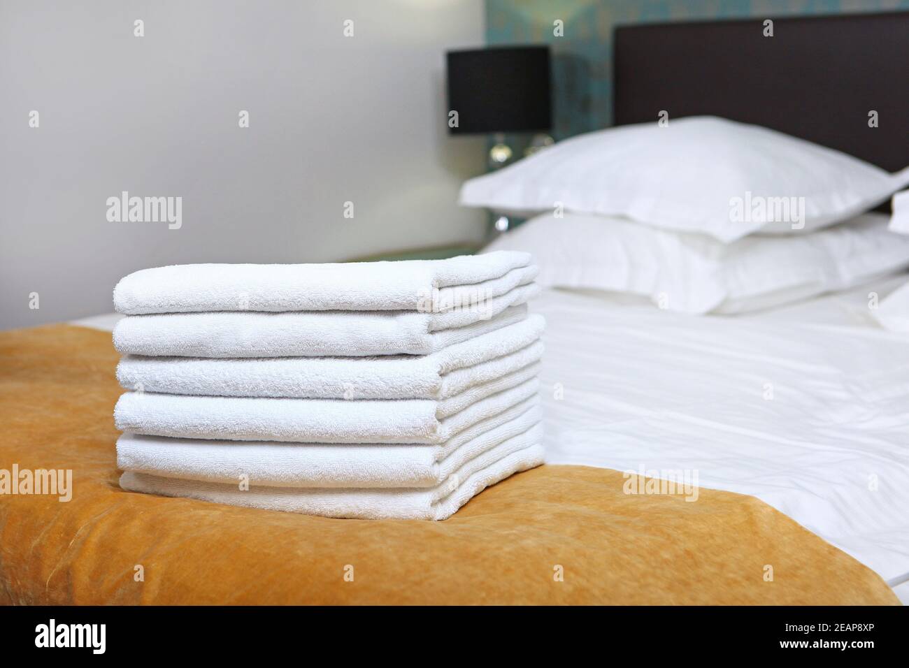 Zimmerreinigung in einem teuren Hotel. Ein Satz saubere Handtücher. Hygieneartikel. Das Doppelbett ist außer Fokus. Das Konzept des Qualitätsdienstes im Hotel. Hotelbusiness. Stockfoto