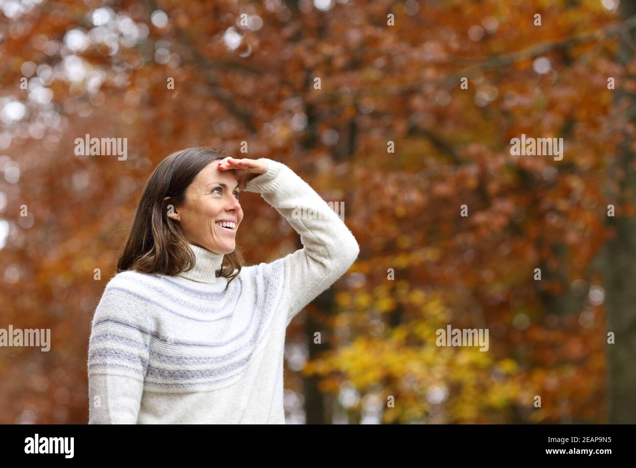Glückliche Erwachsene Frau auf der Suche in einem Wald im Herbst Stockfoto