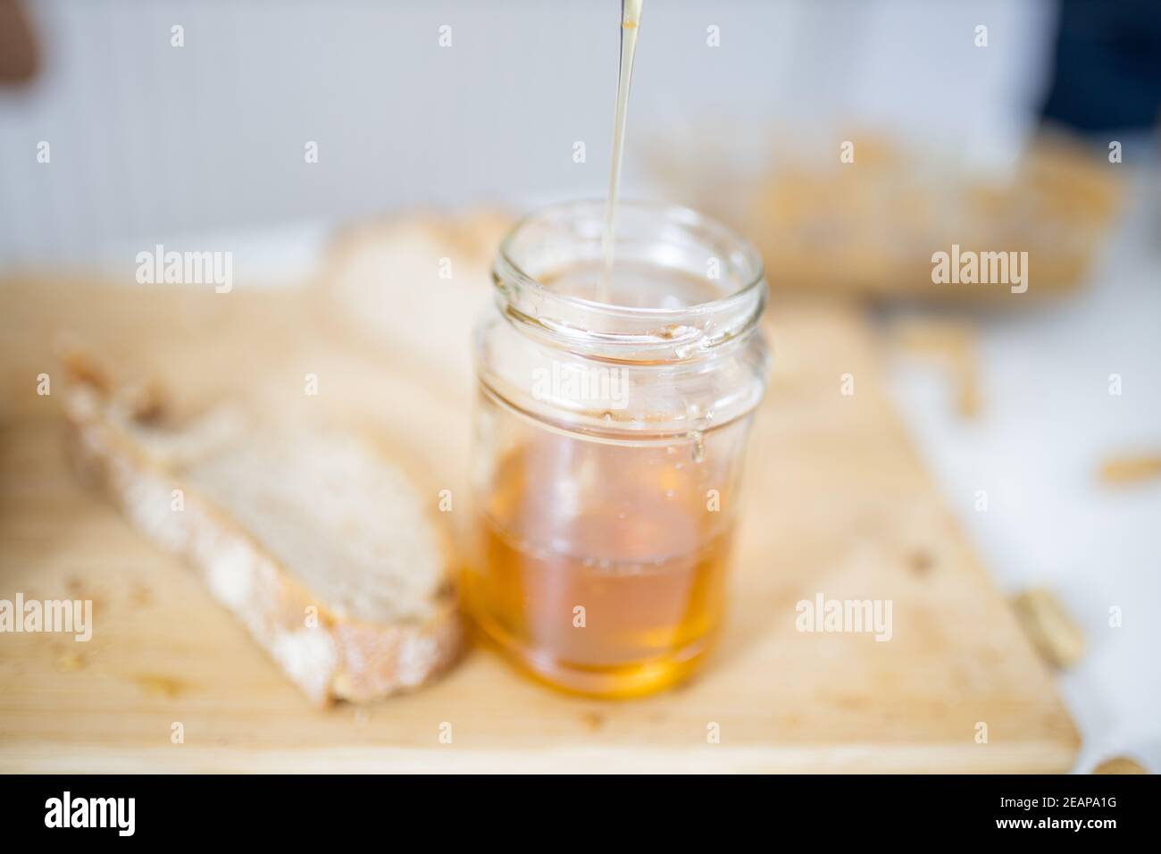 Honigglas und eine Scheibe Brot auf Holzbrett Stockfoto