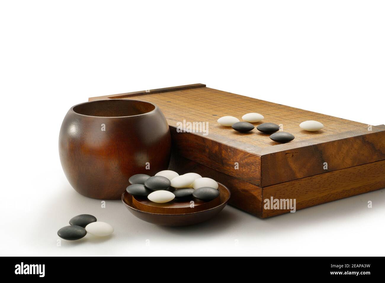 Schwarze und weiße Steine von Baduk Spiel auf Holzbrett Isoliert auf Weiß Stockfoto