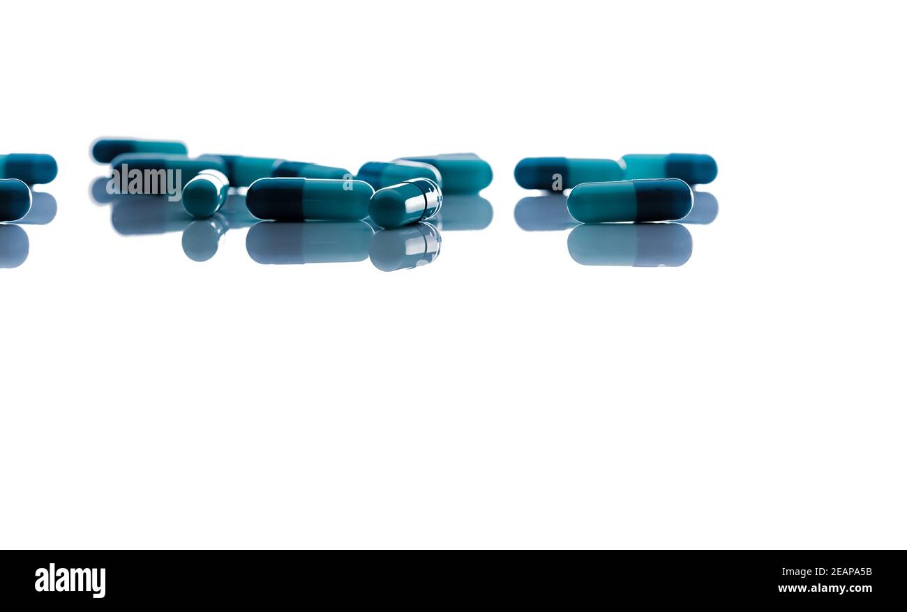 Selektiver Fokus auf blaue Kapsel Pillen. Gruppe von Kapseln Pillen mit Schatten auf weißem Hintergrund verteilt. Apotheke Drogerieprodukt. Gesundheits- und Krankenversicherung Hintergrund. Pharmaindustrie. Stockfoto