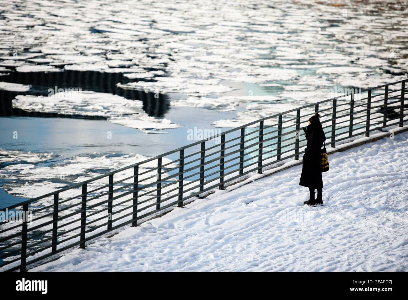 Berlin, Berlin, Deutschland. Februar 2021, 10th. Eine Frau schaut auf schwimmende Eisschilde neben der Spree. Ein Wetterphänomen, die Polarwirbelspaltung genannt, brachte Schnee und eisige Winde nach Berlin und Brandenburg mit Temperaturen weit unter dem Gefrierpunkt. Quelle: Jan Scheunert/ZUMA Wire/Alamy Live News Stockfoto