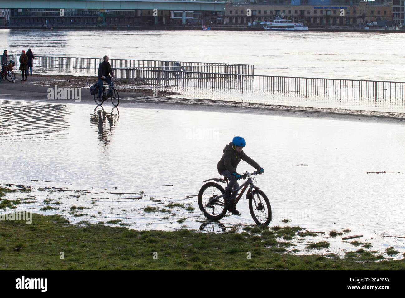 Rheinflut am 4th. Februar 2021 fährt Kind auf dem überfluteten Rheinufer in Deutz, Köln, durch das Wasser. Hochwa Stockfoto