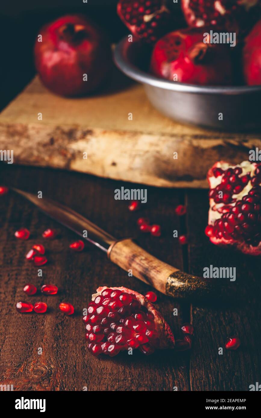Granatapfelfrüchte mit Messer auf Holztisch Stockfoto