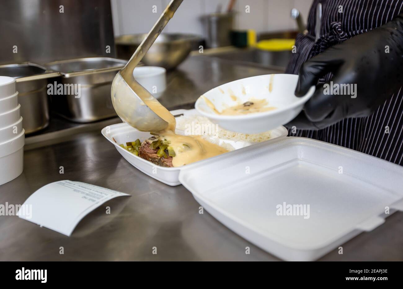 Koch bereitet Gericht zu einer Box in einem Restaurant für die Lieferung von Lebensmitteln nach Hause, Online-Bestellung Stockfoto
