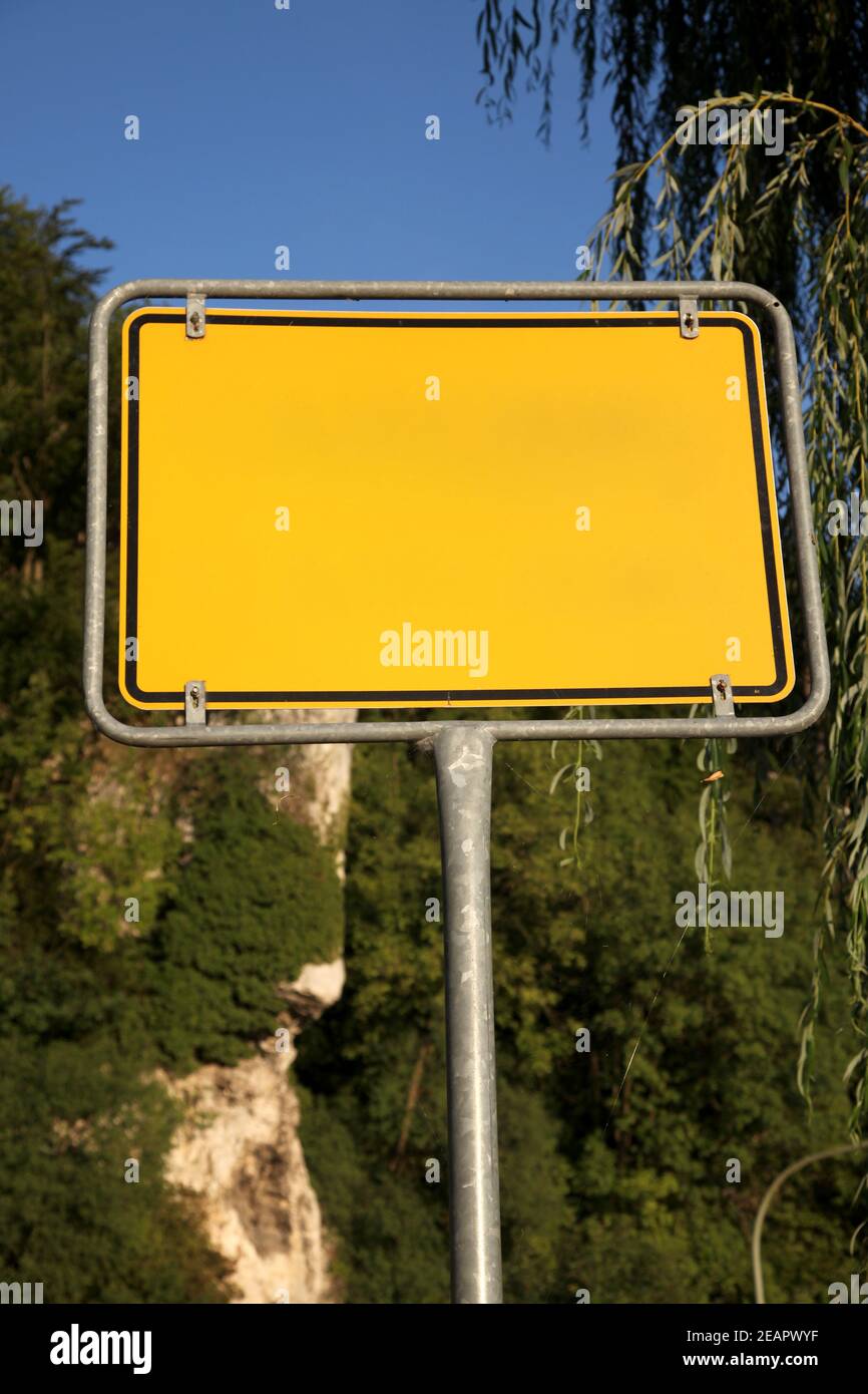Gelbes Straßenschild auf einem Hintergrund von Bäumen Stockfoto