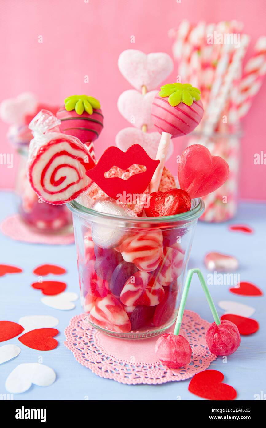 Kleines Glas mit niedlichen herzförmigen Süßigkeiten für Valentinstag Stockfoto