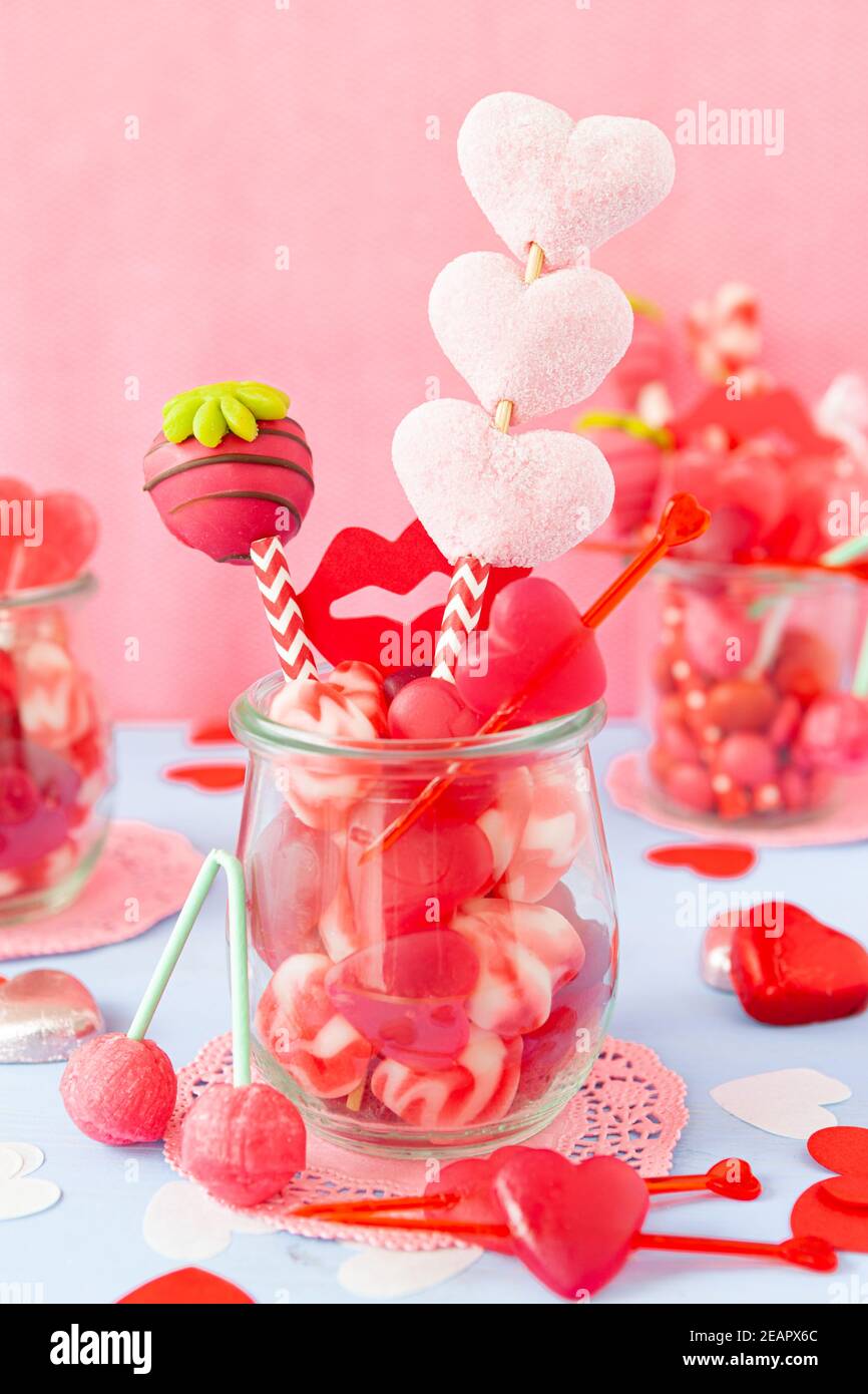 Kleines Glas mit niedlichen herzförmigen Süßigkeiten für Valentinstag Stockfoto