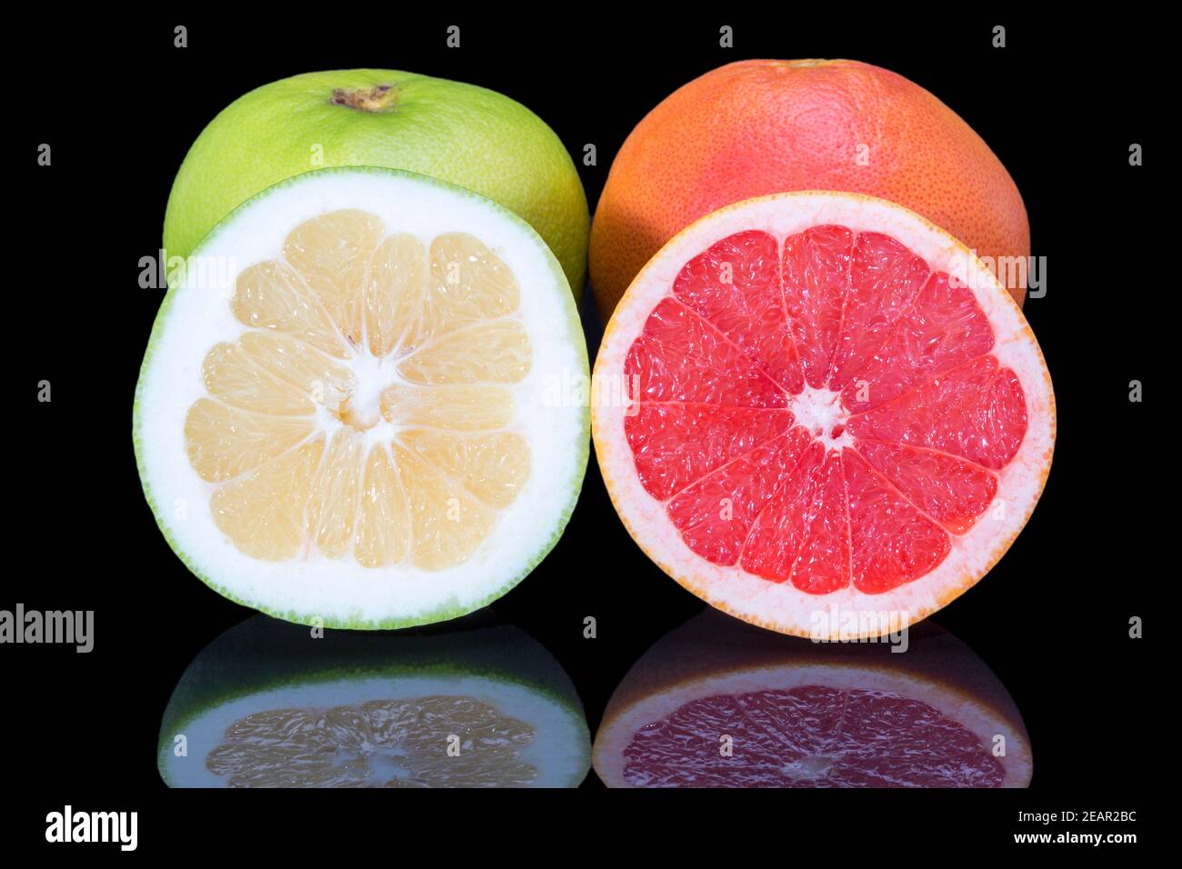 Zitrusfrüchte von roten und grünen Grapefruit ganz und halb Isoliert auf schwarzem Hintergrund Nahaufnahme Stockfoto